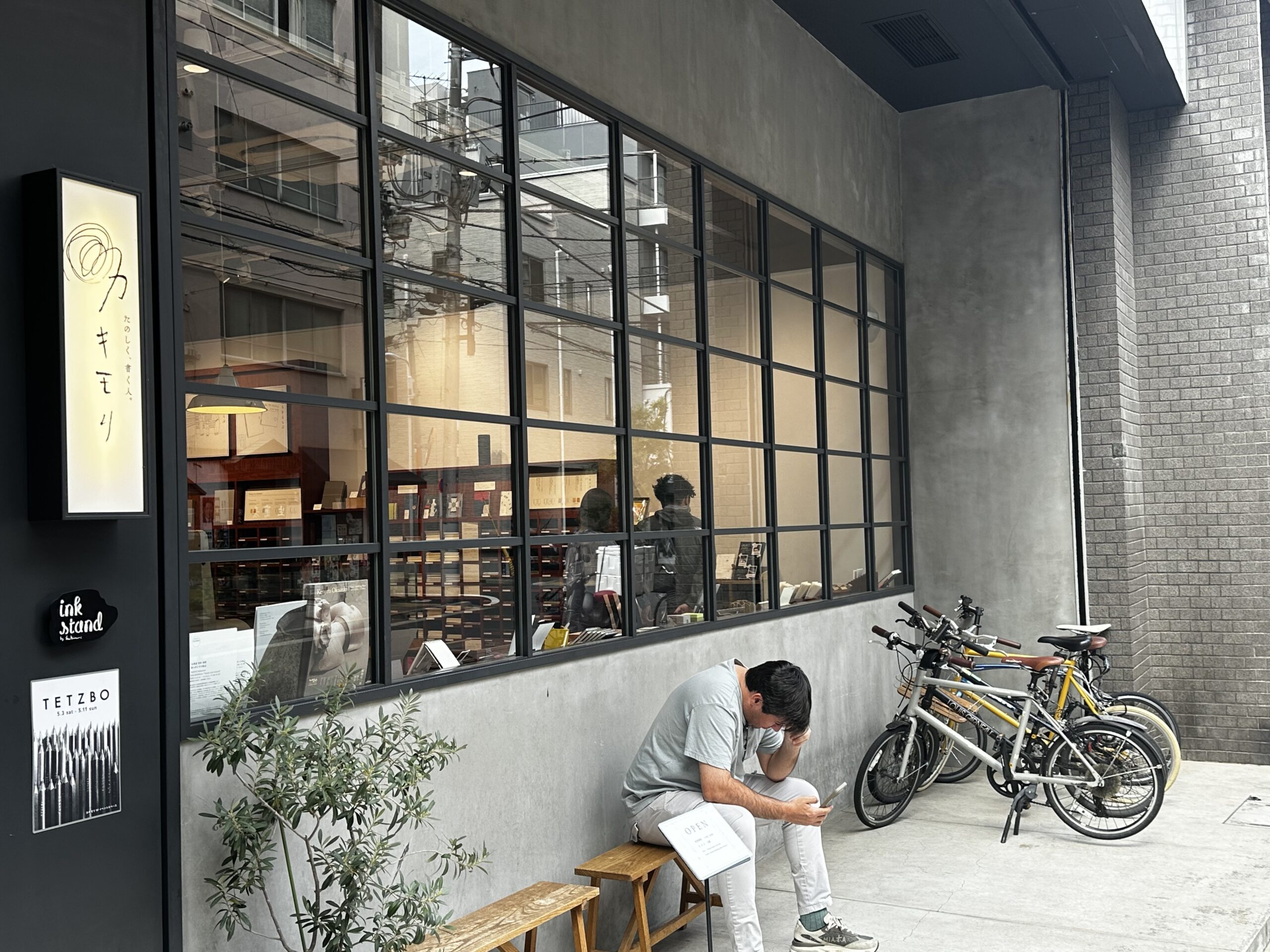 The exterior of Kakimori with large grid windows, a bench, and several bicycles parked outside.