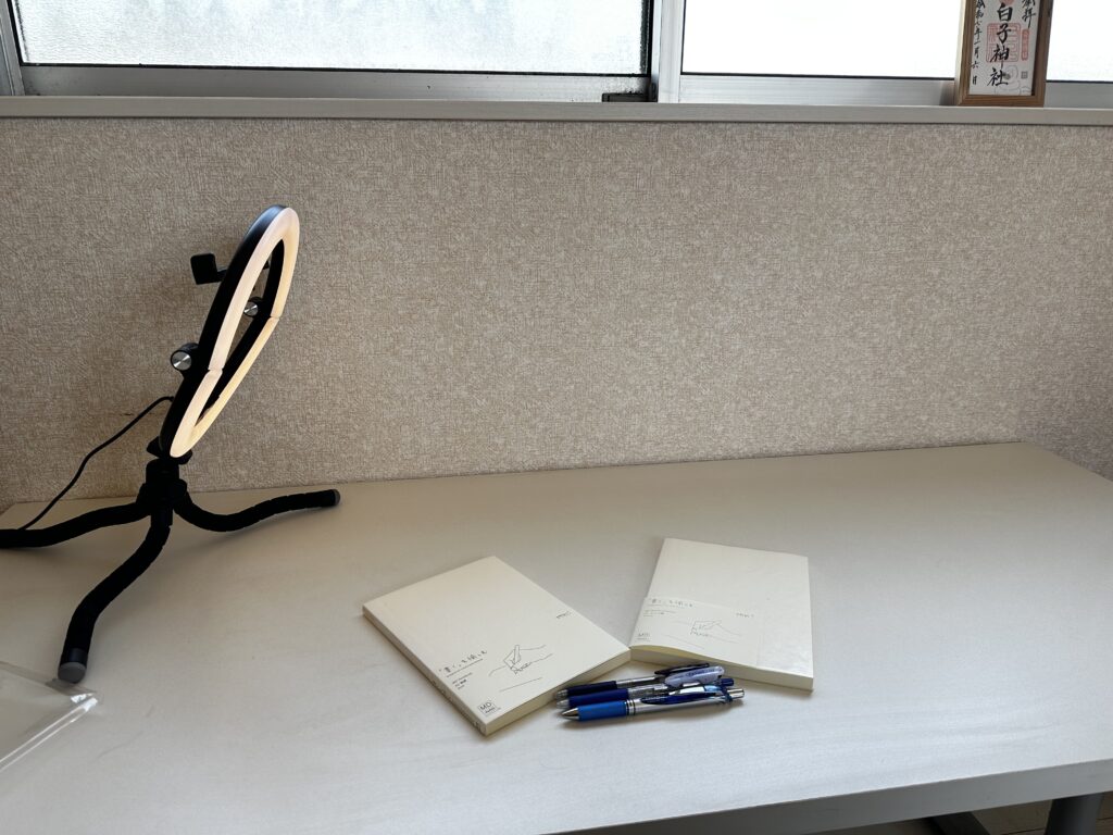 自然光が差し込む部屋で、ノートとペンの撮影準備が整えられている