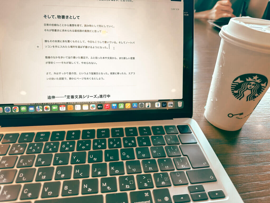 MacBook Airとスターバックスでの記事執筆風景。noteの編集画面に表示されている本文とキーボード、紙カップが写っている