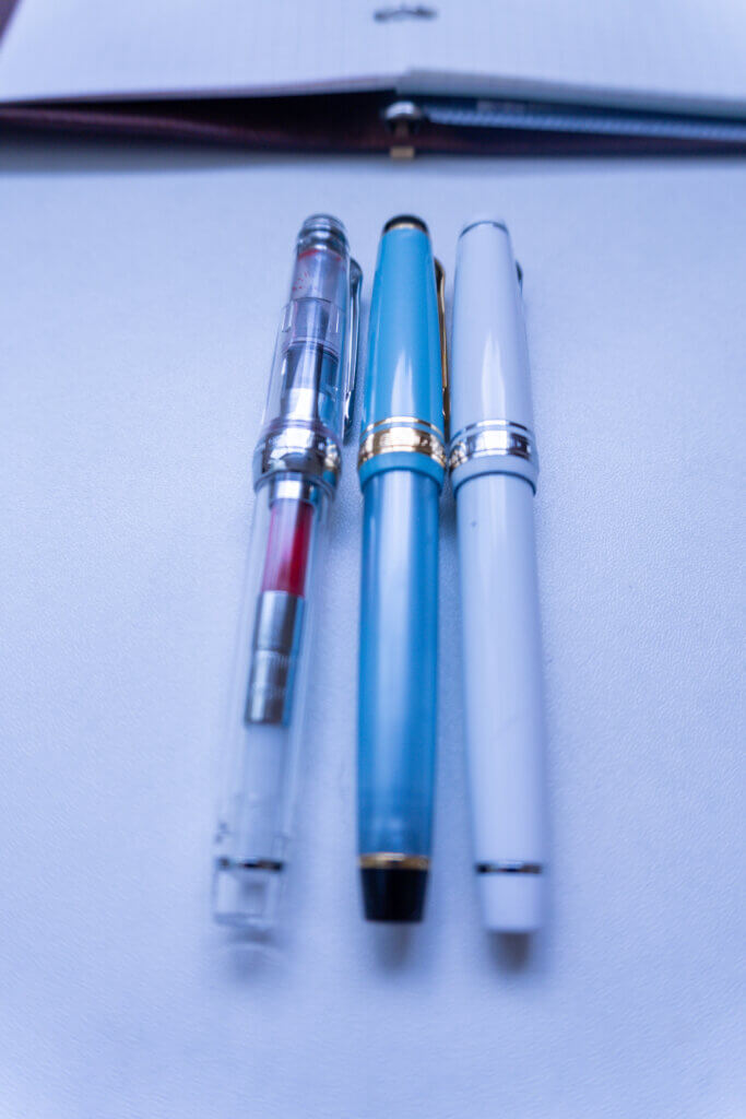 セーラー万年筆「プロギアスリム」透明軸、スカイブルー、白の3本の万年筆を並べた写真。筆記具の比較イメージ。
