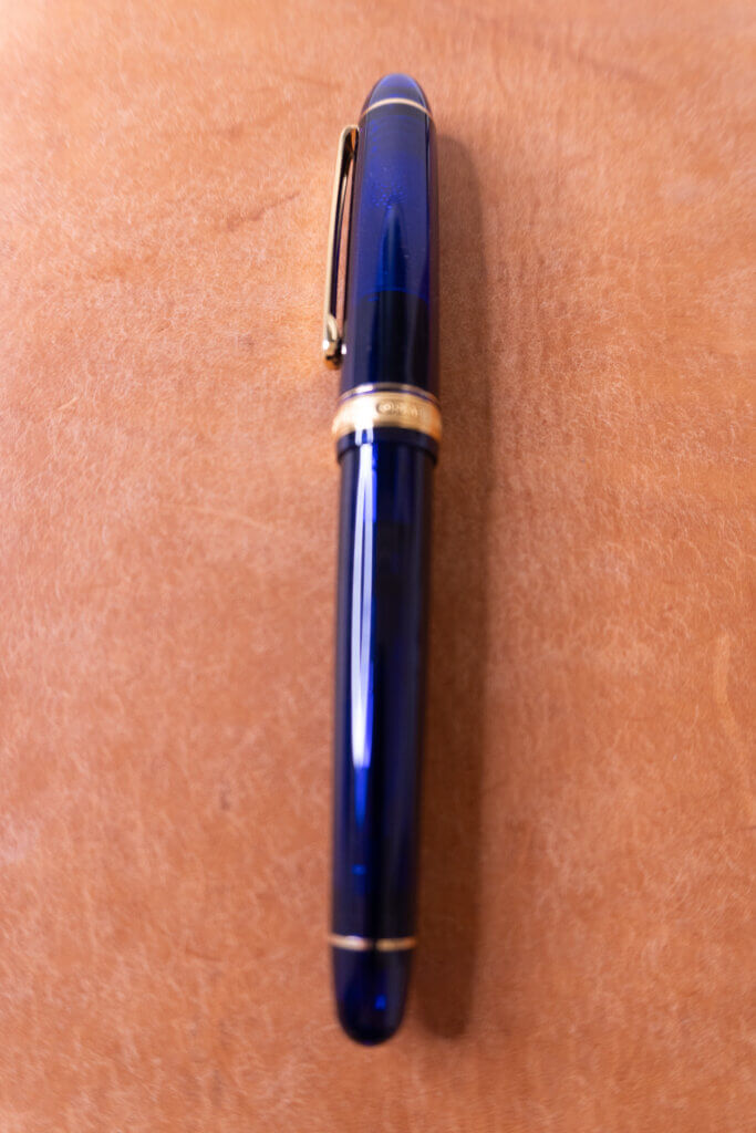 プラチナ万年筆『＃3776 センチュリー（シャトルブルー）』をプロッター A5サイズの革表紙の上で接写した写真