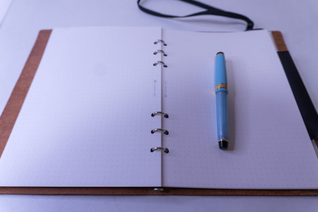 プロッター A5サイズを開き、6穴リングリフィルにセーラー万年筆「プロギアスリム（ブルー）」を置いた写真