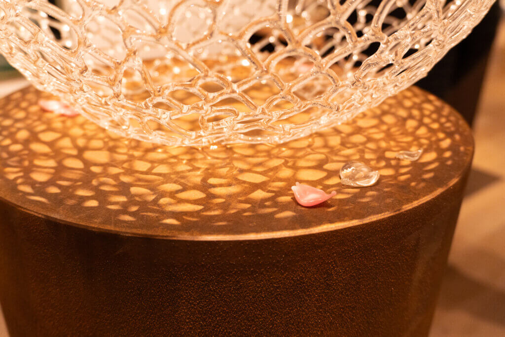 ガラスの球体を支える台座に落ちた花びらのクローズアップ